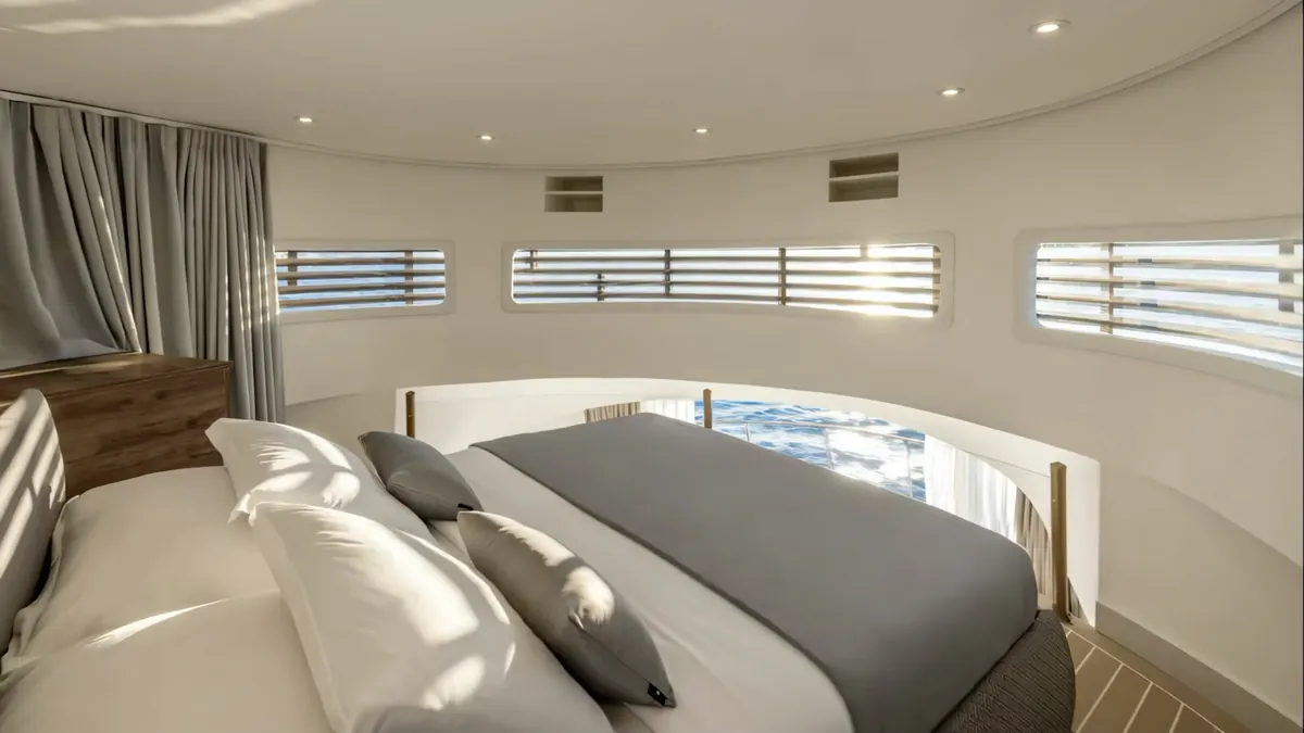 The upper-deck bedroom in morning light, with slatted windows on the curved wall