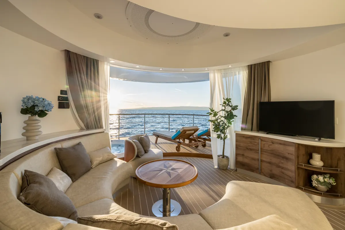 The living deck in daylight: a curved sofa and timber floor, doors open to the front deck