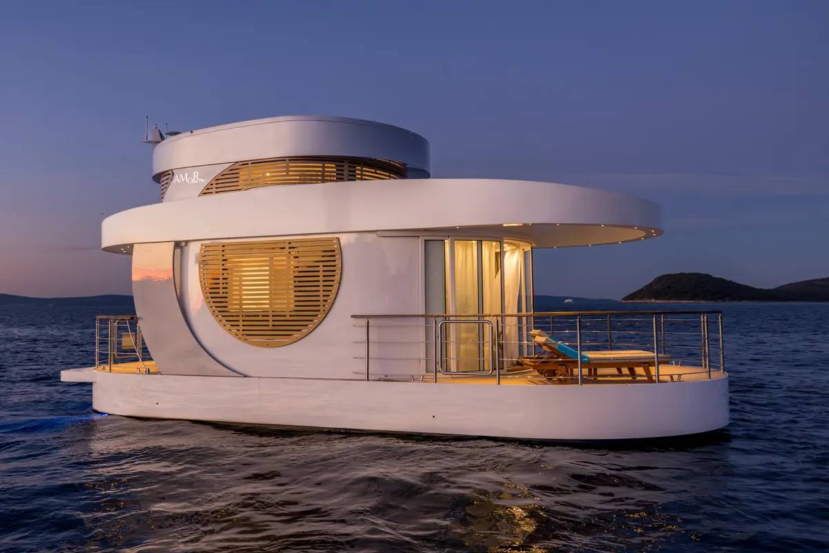 Amor in profile at dusk: two decks, a round louvred window and a front deck with loungers