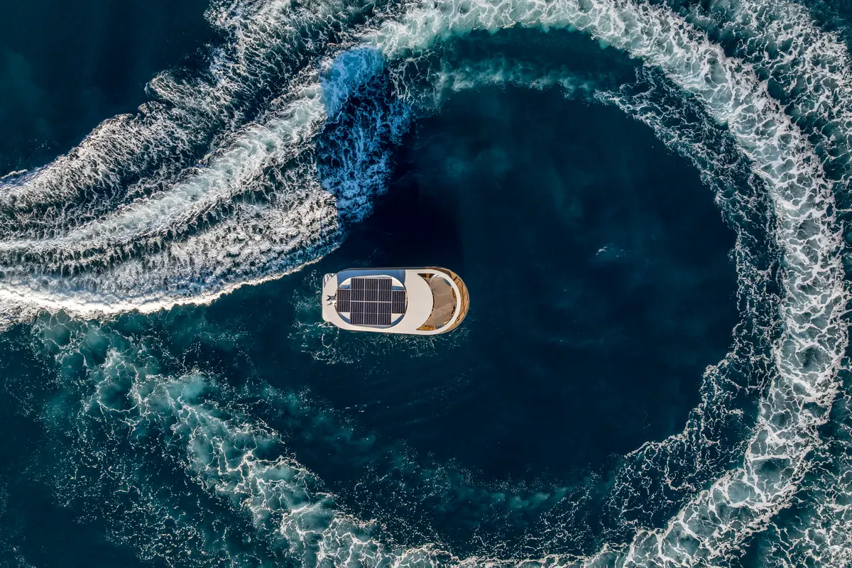 A Watersuite at rest in the centre of a circle drawn by a passing boat's wake, seen from above
